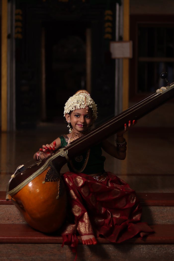 Young girl in traditional Indian attire delicately playing a tanpura, showcasing cultural heritage.